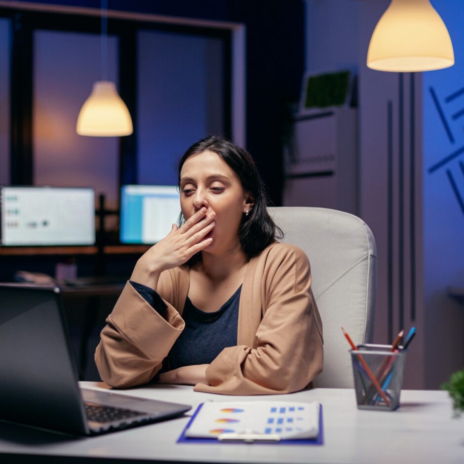 Employee experiencing workplace fatigue and sleep deprivation while working late at a computer