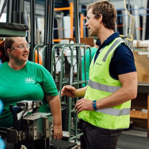 Workplace physiotherapist discussing injury rehabilitation with an employee on the factory floor.
